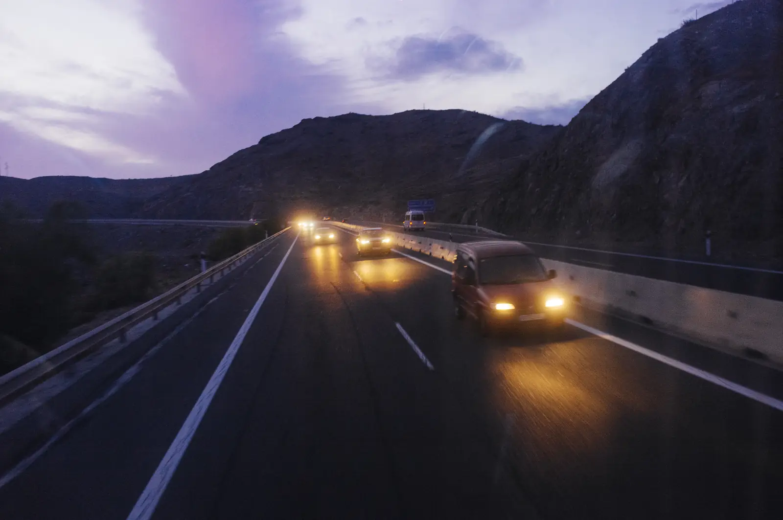 Voitures phares allumés sur une autoroute à la tombée de la nuit